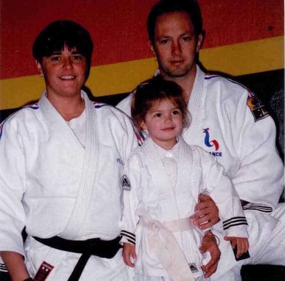 Lisa enfant en kimono de judo entre deux judokas adultes