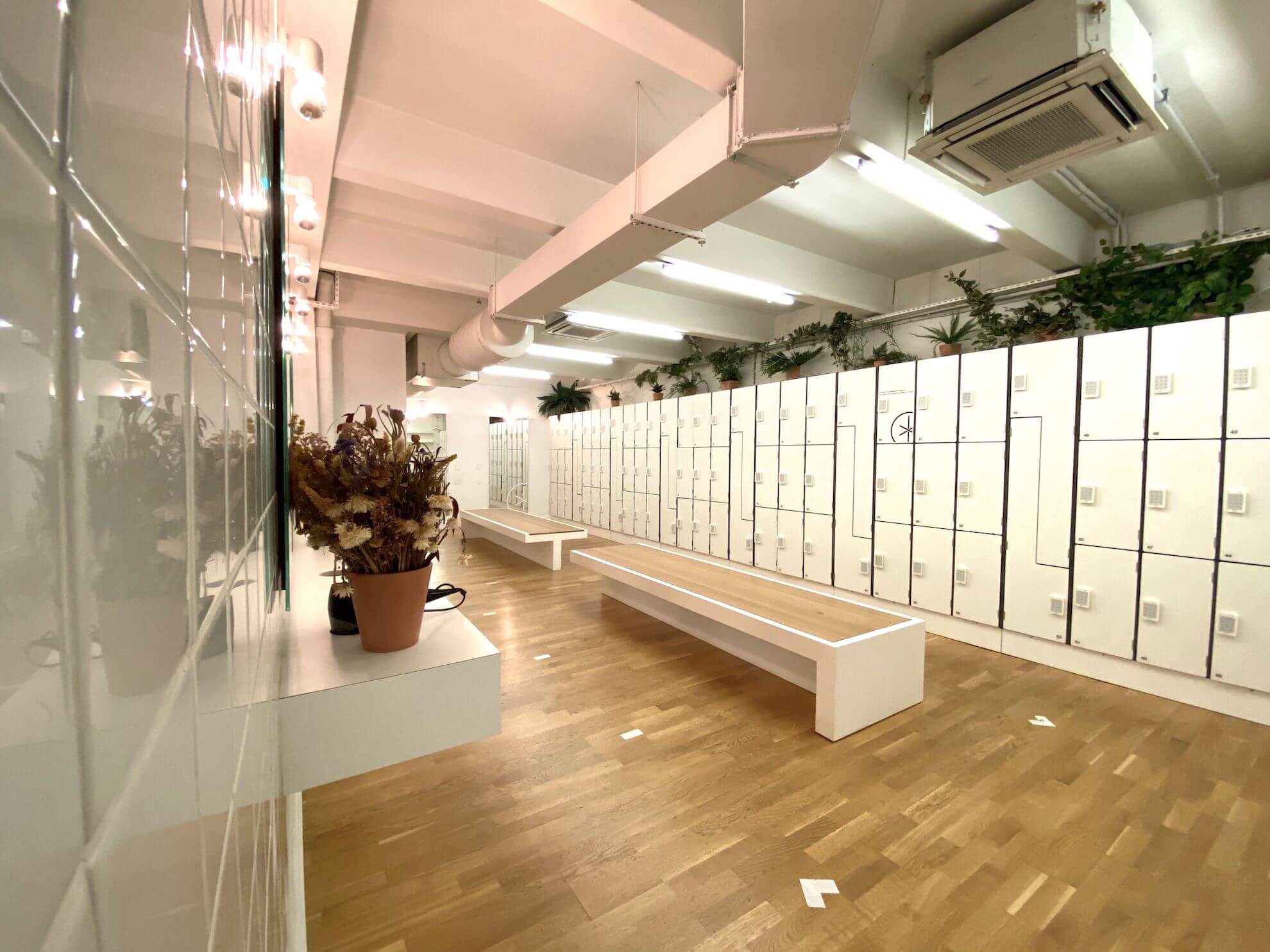 Vestiaires du studio Boétie : casiers blancs, bancs et plantes