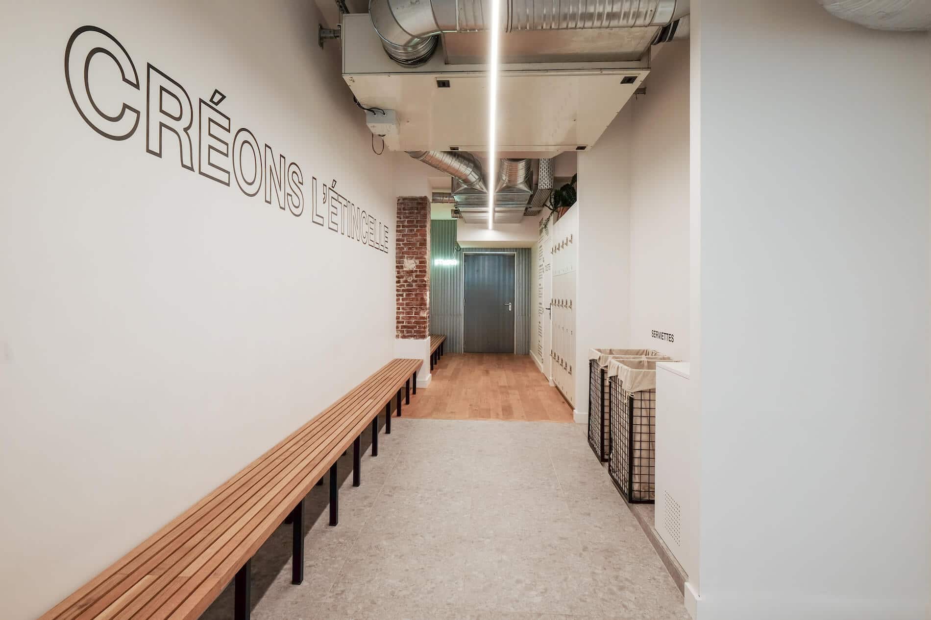 Couloir du studio Villiers, banc en bois et inscription CRÉONS L’ÉTINCELLE