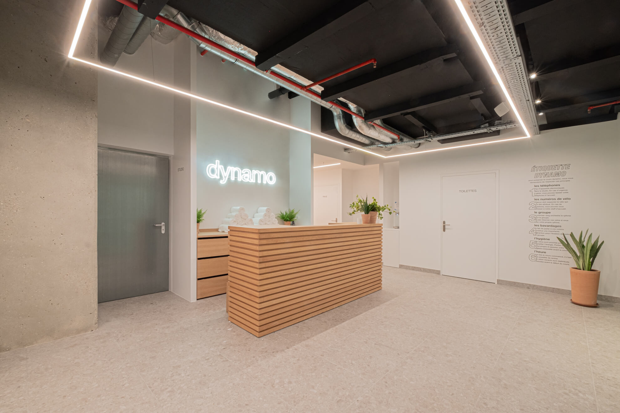 Accueil du studio La Défense, comptoir en bois et enseigne dynamo lumineuse