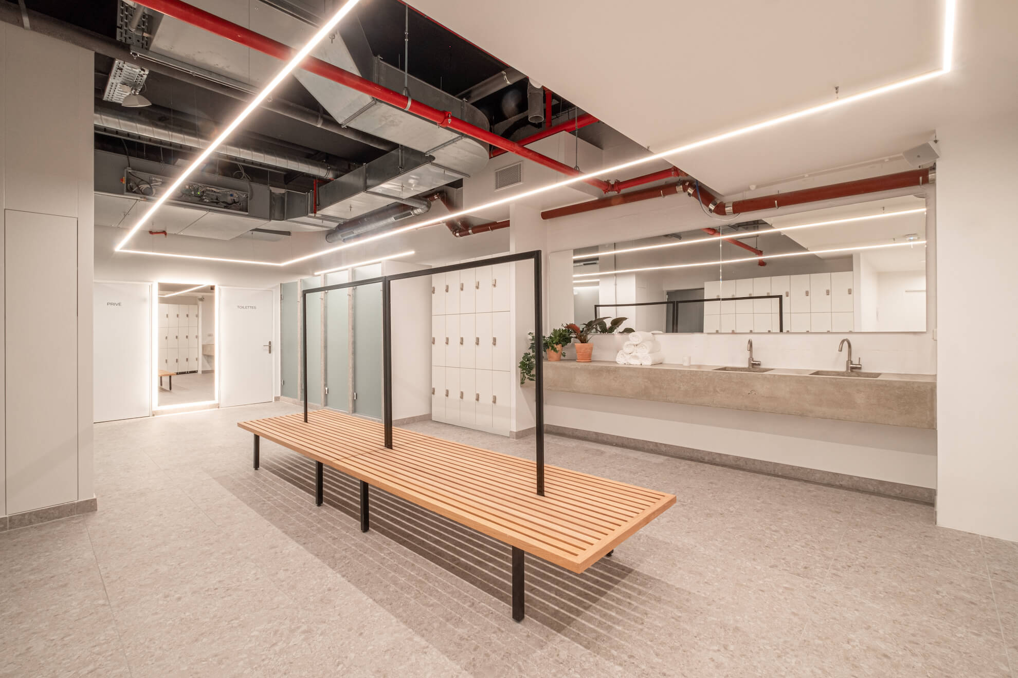 Vestiaires du studio La Défense : banc en bois, casiers et lavabos