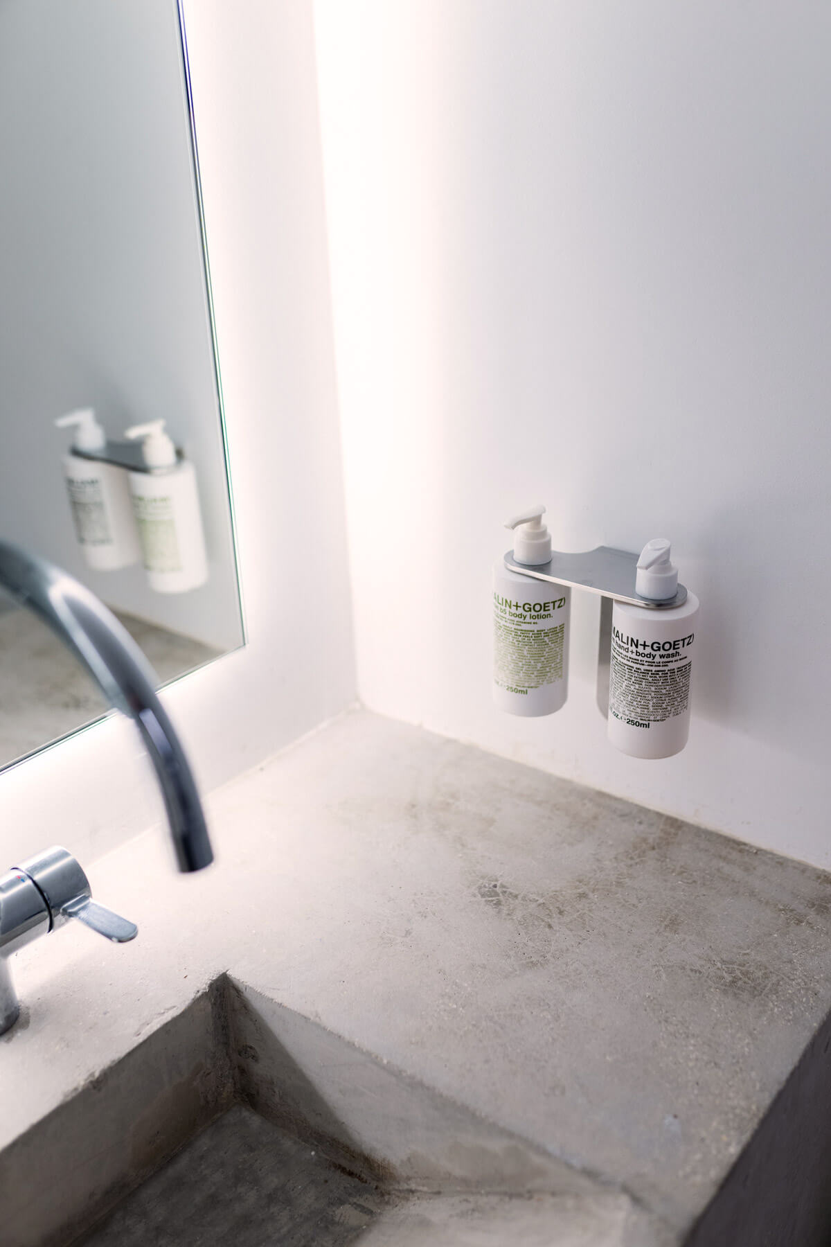 Lavabo en béton et flacons de soin au studio Sèvres